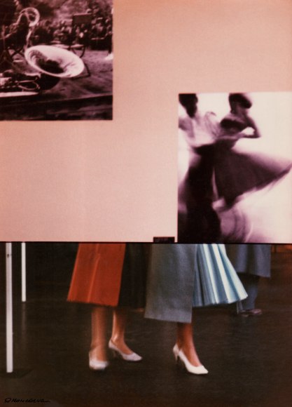Riccardo Moncalvo, Alla Mostra, ​1954. Color photograph. Two figures in white heels and tea-length skirts can be seen in the lower half of the frame, their upper bodies obscured by a wall with two photographs on it.