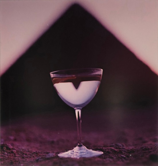 Bert Stern, Martini &amp; Pyramid, for Smirnoff Vodka, ​1955. Martini glass on sand with a triangle shape out of focus in the background.
