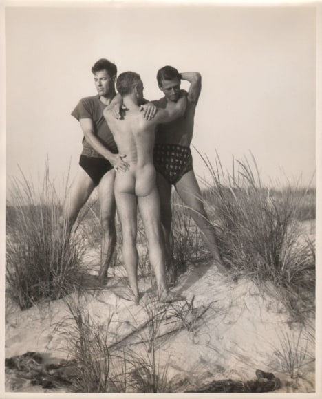 PaJaMa, Glenway Wescott, George Platt Lynes, Paul Cadmus, ​c. 1941. Three men pose together on the beach. Two face the camera, the central nude figure faces away.