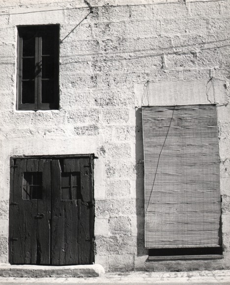 Mimmo Castellano, Bari, ​c. 1960. One face of a stone building. A set of wooden double doors is below a window and beside another opening covered by blinds.