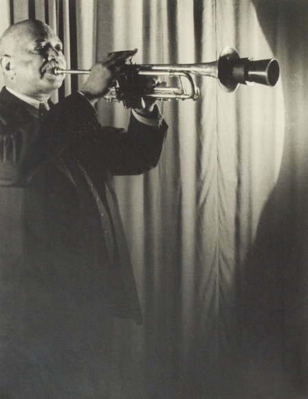 36. Carl Van Vechten, W.C. Handy, 1941. Three-quarter length portrait of subject standing on the left of the frame playing a muted trumpet.