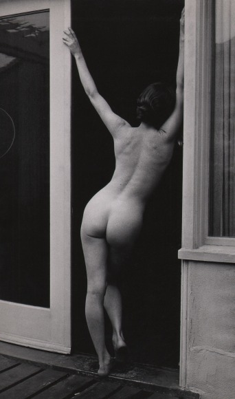 Bob Hollingsworth, Untitled, ​c. 1955&ndash;1960. Nude female figure leans against a door frame with arms raised, back to the camera.