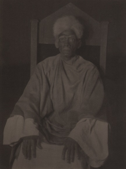 Doris Ulmann, Untitled (Preacher), ​1928&ndash;1934. Dark exposure of a man in robes seated on a chair with a pointed back.