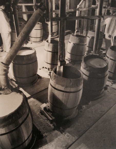 Harold Haliday Costain, Edgewater, NJ Sugar Refinery, ​1935. Barrels are filled with sugar via vertical pipes.