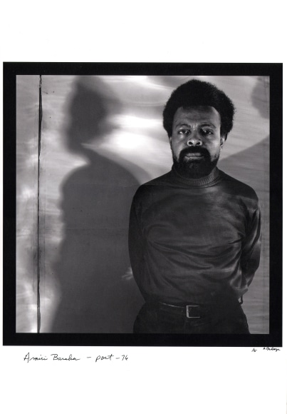 Anthony Barboza, Amiri Baraka - Poet, 1976/2017. Subject stands to the right of the square frame with arms behind his back, looking to the camera. His shadow is cast to either side onto the backdrop.