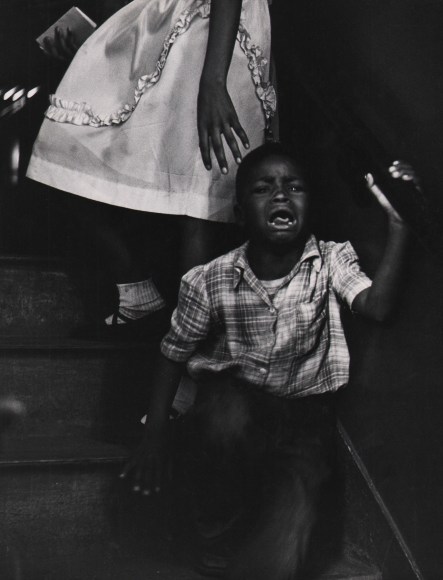 Marvin E. Newman, Chicago, ​1950. A young boy cries, facing away from the skirt of an adult female figure pictured from the waist down.