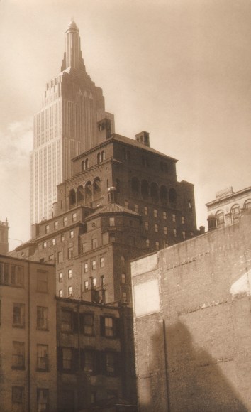 Paul J. Woolf, Empire State from Park Avenue, c. 1933. Shorter buildings converge in the foreground with the Empire State Building in the upper left of the frame in the background.