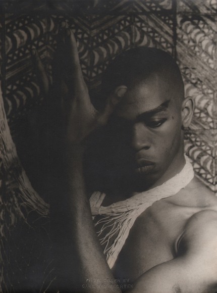 Carl Van Vechten, Geoffrey Holder, ​1954. Subject poses shirtless with one hand raised by his face, eyes cast downward.
