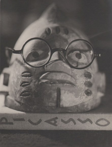 Claude Tolmer, Still Life, ​c. 1933. Small head sculpture with eyeglasses placed on it, resting on a book with &quot;Picasso&quot; on the spine.