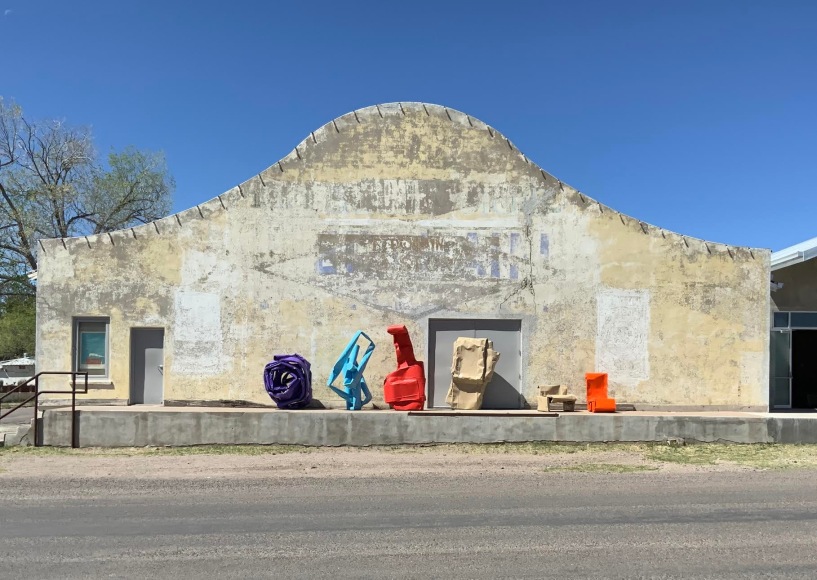 Six sculptures lined up in front of a building's facade in Marfa, Texas.
