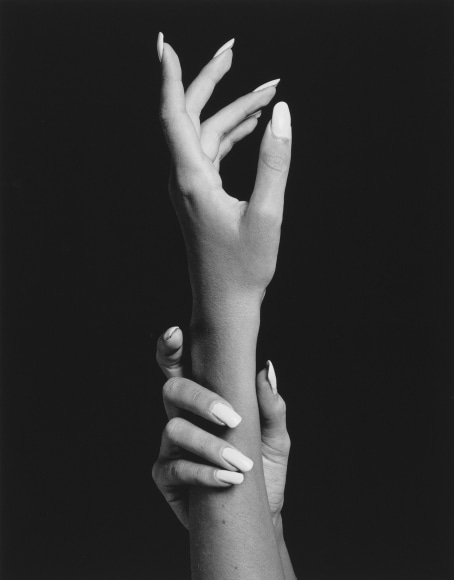 Portrait of two hands with long fingernails, one hand grasping the wrist of the other.