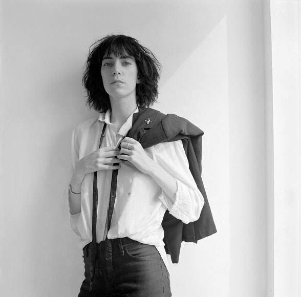 Patti Smith facing camera, suit jacket draped over shoulder.