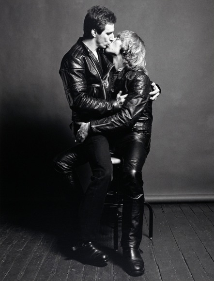 Larry and Bobby sitting in one chair, kissing.