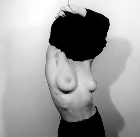 Lisa Lyon pulling shirt over her head.