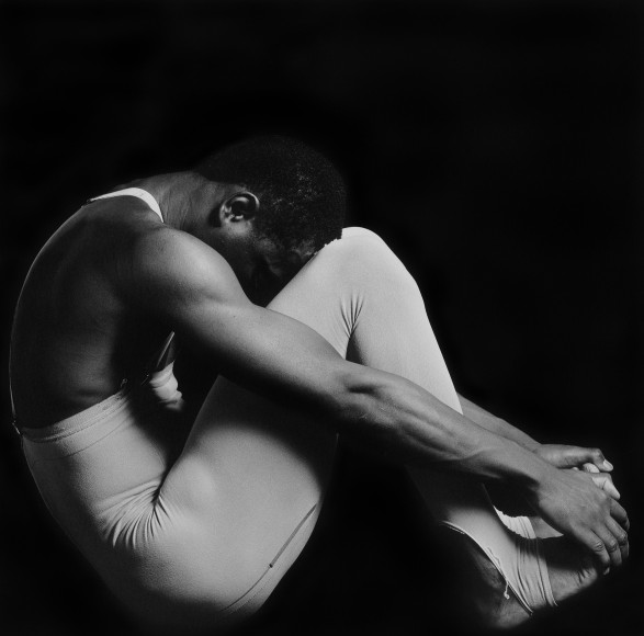 Clifton in profile, seated, wearing tights and grabbing at feet.