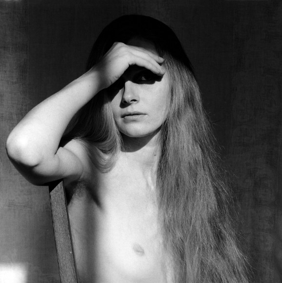 Carol Overby, nude, hand above eye to block light.