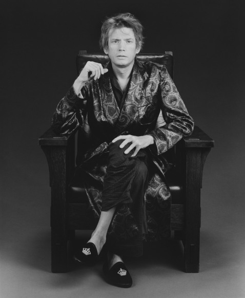 Man seated in chair with geometric robe.