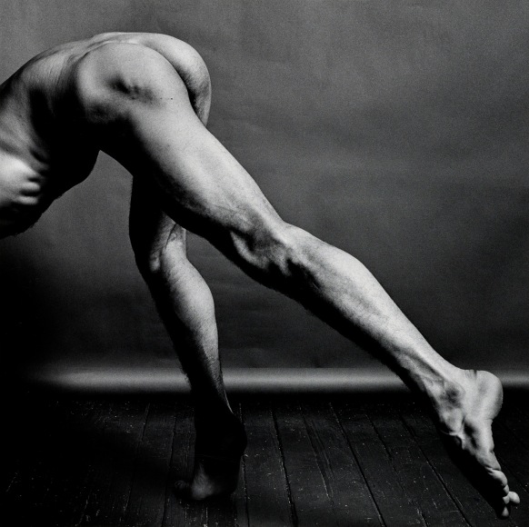 Nude dancer bending down, head out of frame.