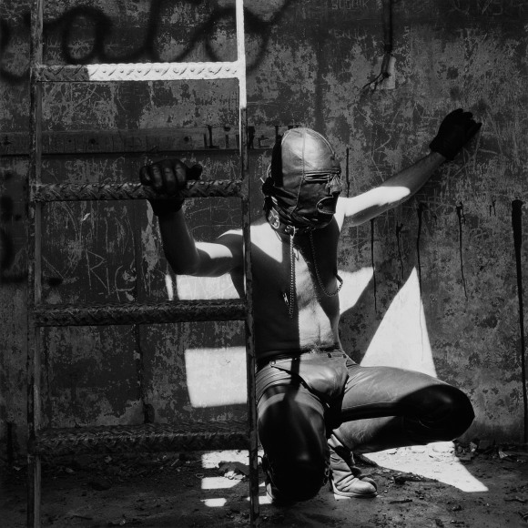 Jim in leather outfit holding staircase.