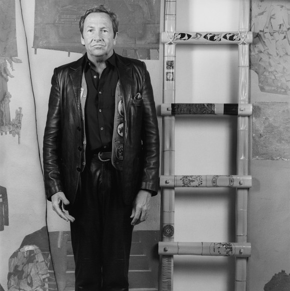 Portrait of Robert Rauschenberg standing next to ladder.