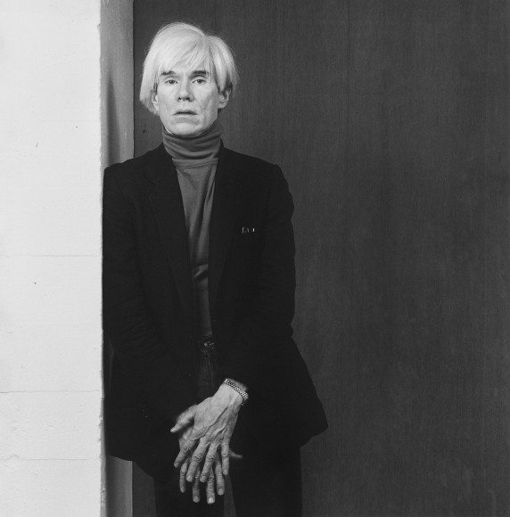 Andy Warhol leaning against a wall.