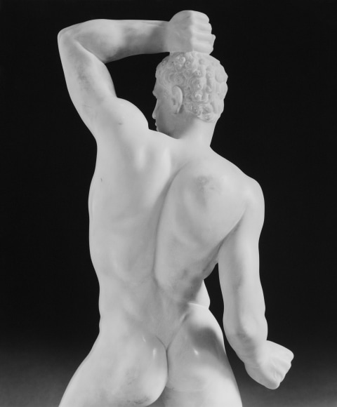 Statue of male body from behind.