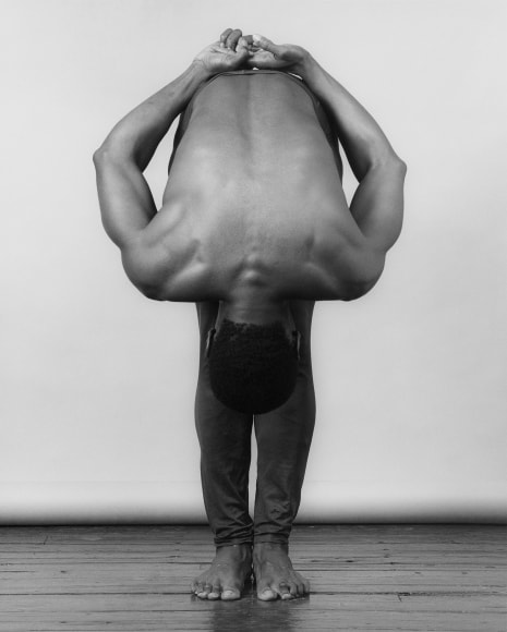 Derrick Cross, two feet on the ground, bending over with head in front of his knees.