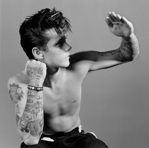 Portrait of person with tattoos with hand up.