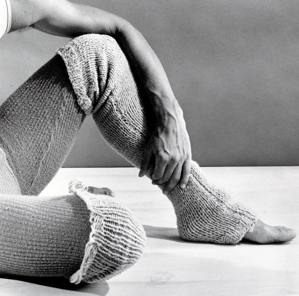 Dancer's arm outstretched over their legs.