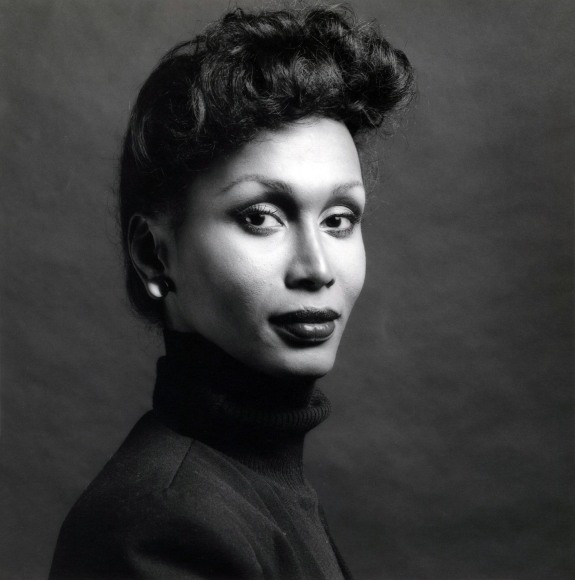 Close-up of a woman in a turtleneck turning to look into the camera.