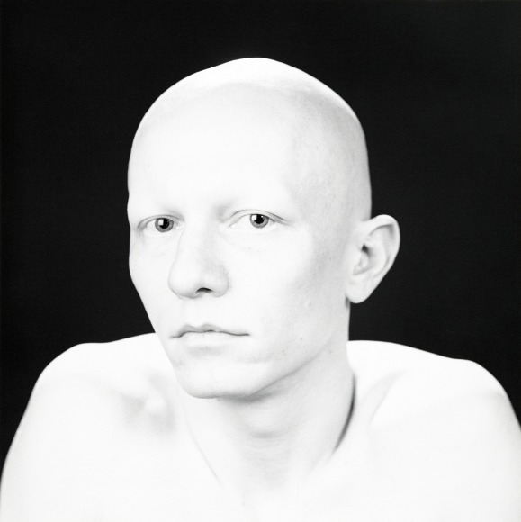 Robert Sherman photographed from the shoulders up, topless and looking at the camera