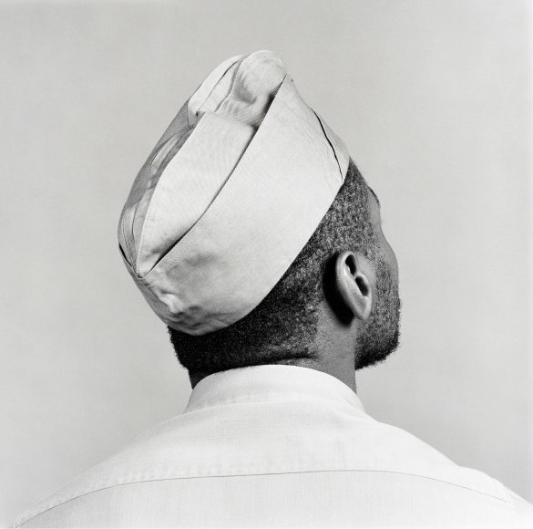 Jack Walls wearing military-style hat, facing away from camera.