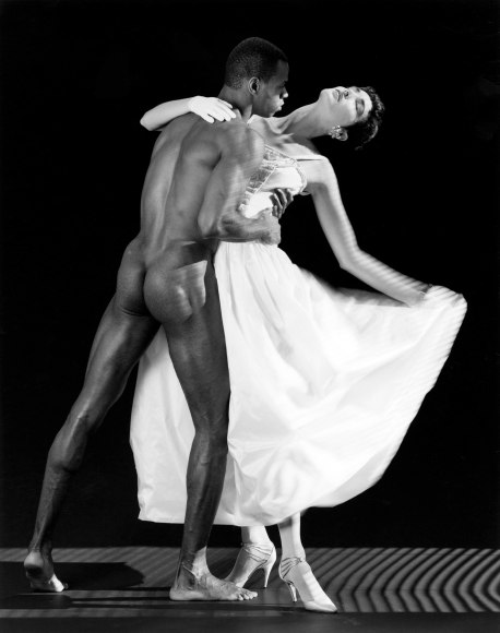 Nude black man dancing with woman in white dress