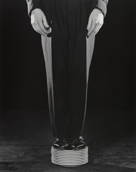 Person in suit standing on stack of plates.