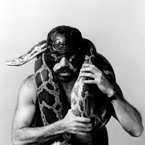 Man wearing mask, holding snake.