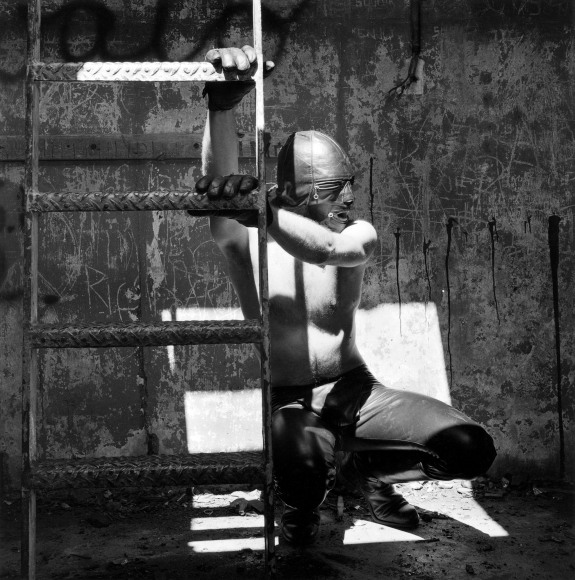 Jim in leather outfit holding staircase.