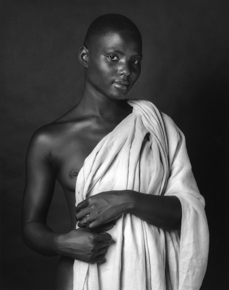 Nude black woman holding up a cloth.