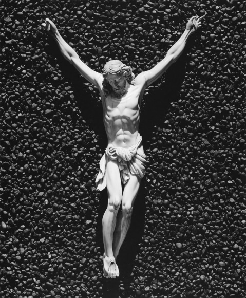 A white crucifix attached to a textured black stone surface.