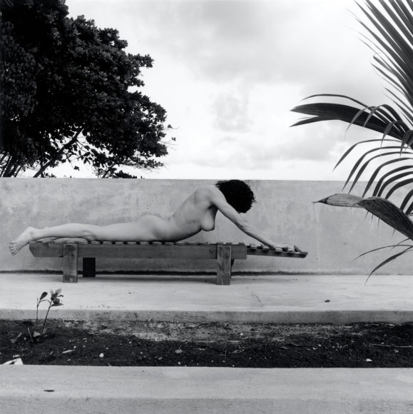 Lisa Lyon lying face down across a bench.