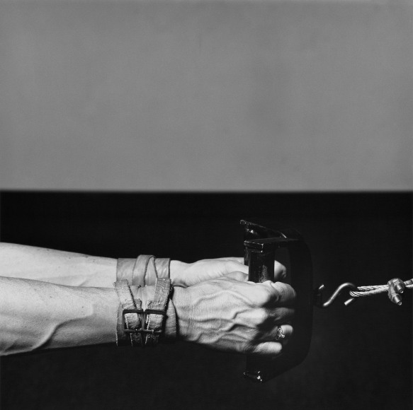 Lisa Lyon's hands grabbing at weight, with leather buckle bracelets.