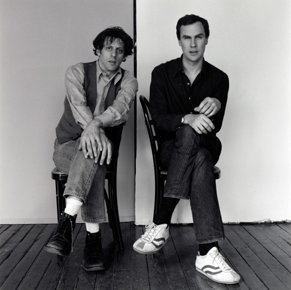 Philip Glass and Robert Wilson seated on chairs, facing camera.