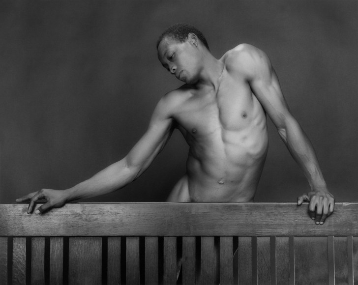 Black male nude posing and looking down.