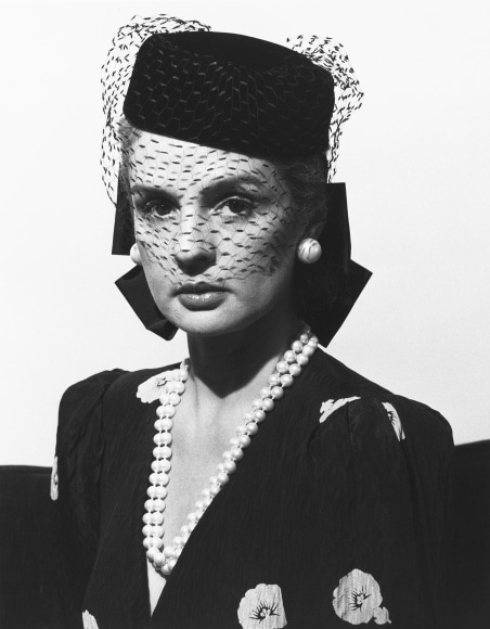 Close-up of fashion designer Carolina Herrera wearing a birdcage hat and pearl jewelry.