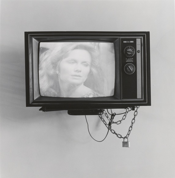 Television with woman on the screen, with lock and chain hanging off.