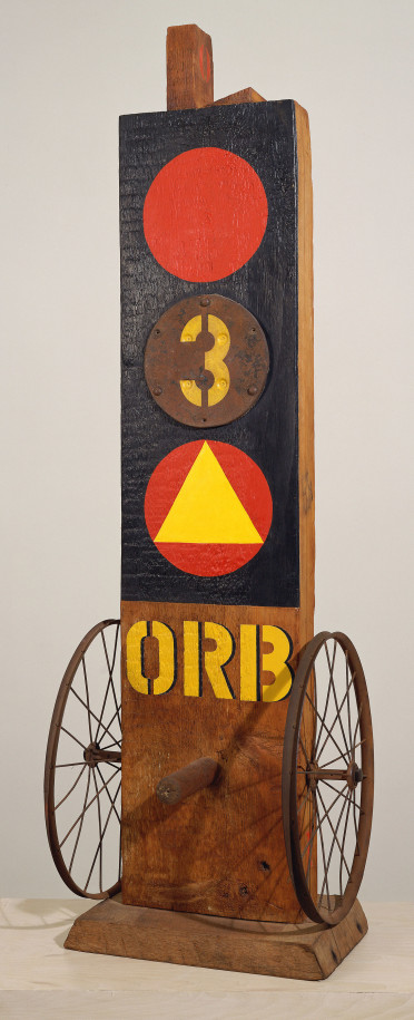 A 62 by 19 1/2 by 19 inch sculpture consisting of a wooden beam with a tenon, on a wooden base. A wheel has been affixed to the lower right and left sides of the sculpture, in between the wheels, protruding from the front of the sculpture, is a wooden peg. In between the upper edges of the wheels is the sculpture's title, &quot;Orb,&quot; painted in yellow stenciled letters. Above the title the front of the sculpture has been painted black, with three circles in a vertical row. The top and bottom circles are red, and a yellow triangle has been painted in the lower circle. The inner circle is a metal plate with a white numeral three.