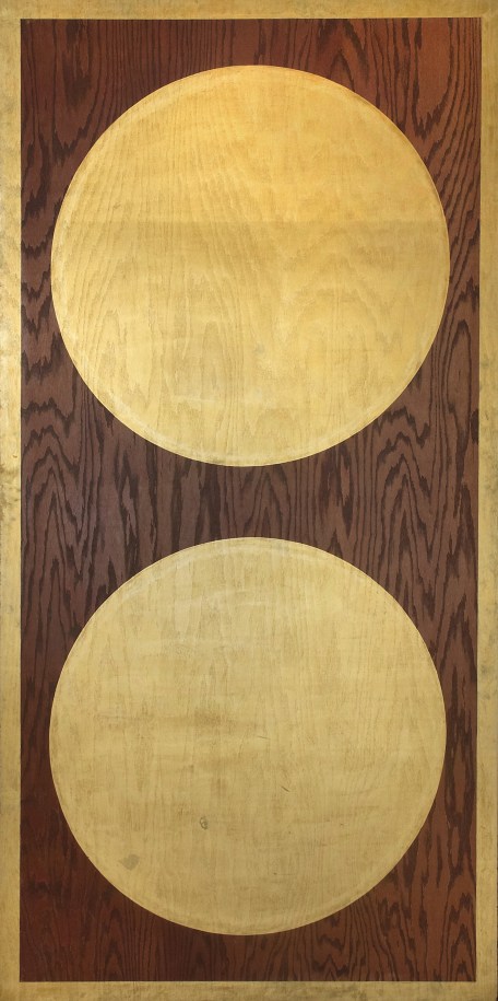 Two large golden orbs on a plywood panel. A gold stripe along all four edges of the panel surrounds the two orbs.