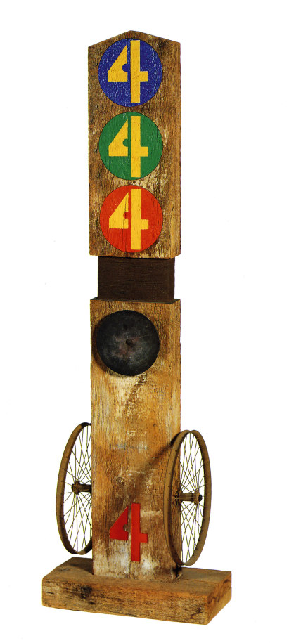 Four is a 77 3/4 by 24 by 12 inch sculpture consisting of a wooden beam on a wooden base. The sculpture is divided in half by thinner section wrapped in thin iron wire. A red number four has been painted at the bottom front of the lower half, and a wheel has been attached to the left and right sides. An iron disk has been affixed to the front of the sculpture just below the wired section. The top part of the sculpture contains three circles with a yellow number four inside. The top circle is blue, the middle circle green, and the lower circle red.