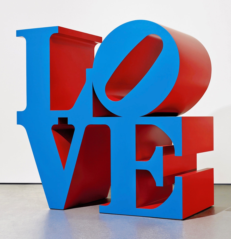A polychrome aluminum sculpture spelling LOVE, with blue faces and red sides. The letters &quot;L&quot; and a tilted &quot;O&quot; rest on top of the letters &quot;V&quot; and &quot;E.&quot;