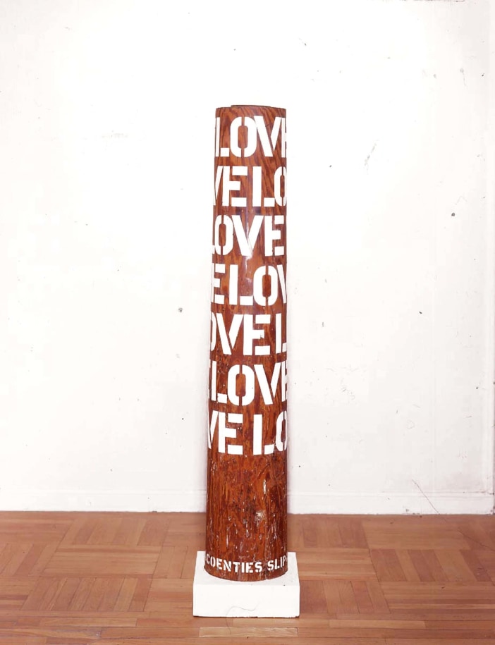 A column with five rows of the word love in gesso stenciled letters wrapping around the upper two thirds of the sculpt