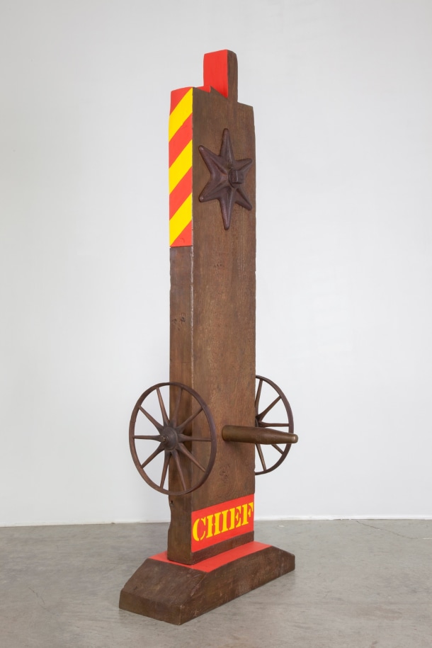 A 63 13/16 by 23 1/8 by 9 1/8 inch painted bronze sculpture of a beam with a haunched tenon, and on a base. The sculpture's title, &quot;Chief,&quot; is painted in yellow stenciled letters against a red rectangular ground across the bottom of the work. Above the title a wheel is attached to the right and left sides of the sculpture, and a peg has been placed in the front of the sculpture, in between the wheels. At the top of the sculpture is a six pointed star. The top third of the right and sides of the sculpture are painted with diagonal red and yellow stripes, and the sides left and right sides of the tenon are painted red.